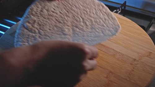 Placing Wholegrain Tortilla Wrap On Wooden Board. Healthy Food Prep In The Kitchen. close up