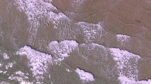 Aerial drone overview of gentle ocean waves rolling onto sandy shores at Sperlonga beach in Italy