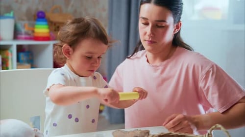 Woman and Child Play with Clay Indoors