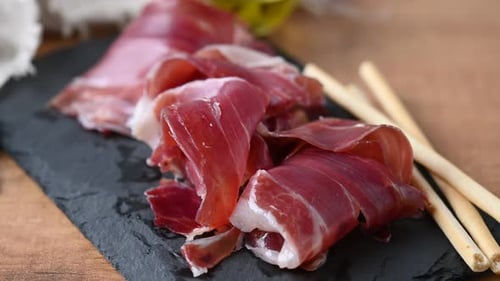 Delicious Prosciutto Slices Served with Breadsticks on Slate