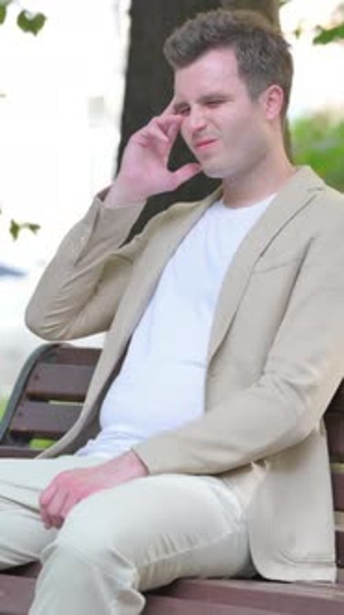 Man Sitting on Park Bench with Headache
