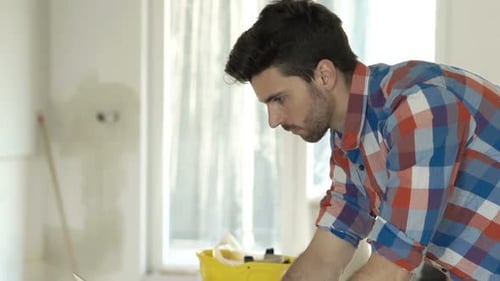 Focused Man Types on Laptop During Home Renovation