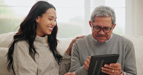 Woman Helps Senior Man with Tablet at Home