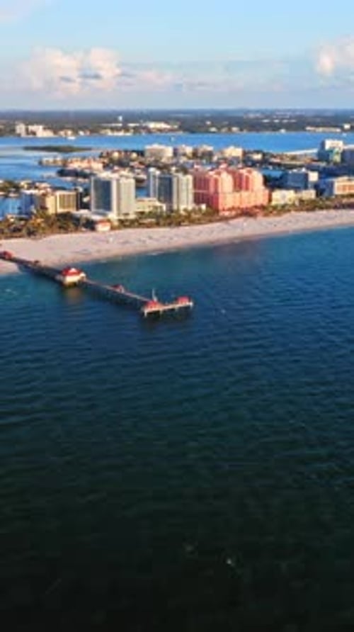 Píer que se estende até o oceano azul profundo com o horizonte da cidade costeira ao fundo