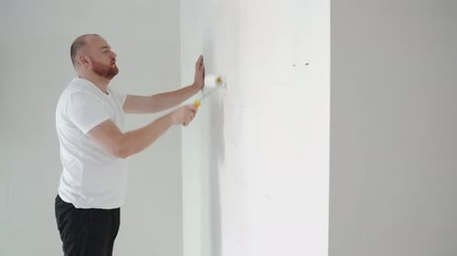 Man Painting a Wall with a Roller