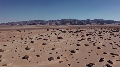 The Expansive Desert Terrain Features Rocky Formations and Mountains Set Against a Bright Sky
