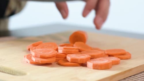 Close-up of Woman's hand cutting a carrot.Side frame, focused on the cut carrots.