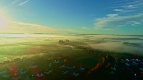 Foggy Clouds Scattered Over Countryside Village At Sunrise. Aerial Shot
