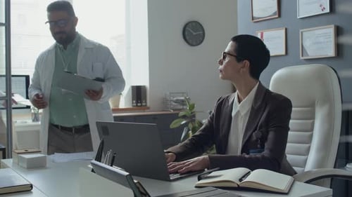 Female Clinical Director Greeting Doctors before Team Meeting in Office