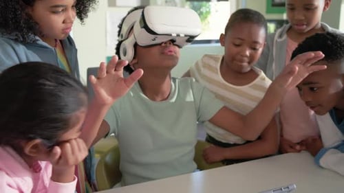 African-American teen girl with VR headset, mint tee, gesturing to VR demo, tapping tablet in class