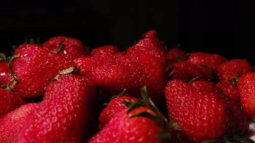 Frische reife Erdbeeren rotieren auf schwarzem Hintergrund