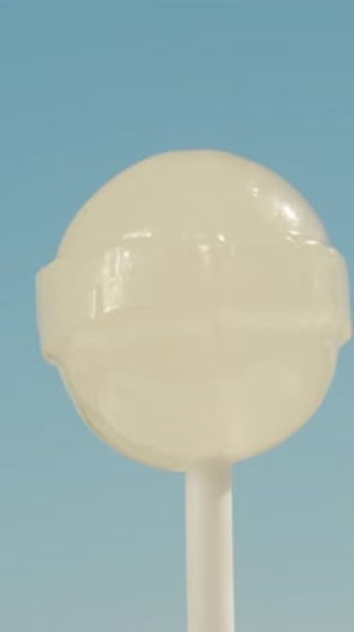 A round white lollipop on a stick, spinning against a blue sky background. Vertical, Social Media