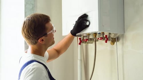 Man Adjusting Boiler In Home