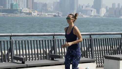Young sporty woman jogging in city by river in super slow motion