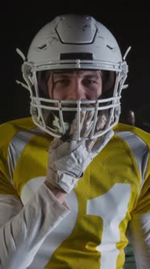Vertical of Gridiron Footballer Putting in Mouthguard and Beating on Helmet