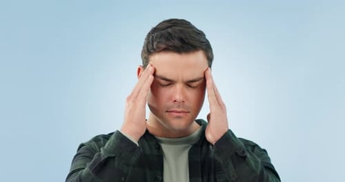 Anxiety, headache and man in studio with stress, vertigo or mental health crisis on blue background