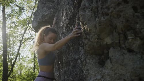 Strong Woman Climbs on Steep Rock During Hike on Summer Day
