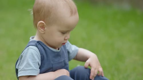 Kaukasischer Overall für Babys und Kleinkinder im blauen Strampler auf grünem Gras