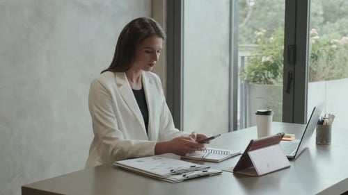 Woman at Desk Uses Mobile Phone