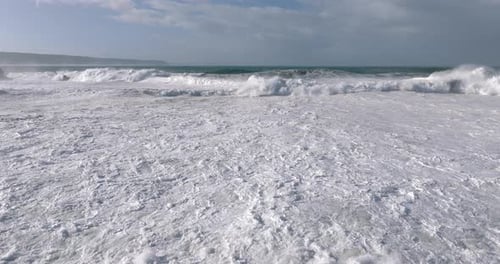 Aerial drone shot of big waves coming into shore on a day with giant waves in Nazaré, Portugal,