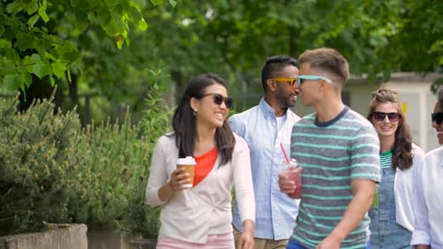 Friends Strolling in Park with Drinks and Coffee