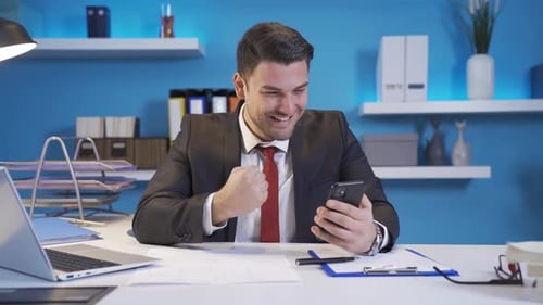 Businessman Using Smartphone Celebrating Success in Office