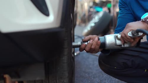 Mechanic Changing Tire on Car with Power Tool
