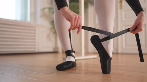 Ballerina Puts on Pointe Shoes on Leg in Dance Class Classical Ballet Dancer Woman in Dance Studio