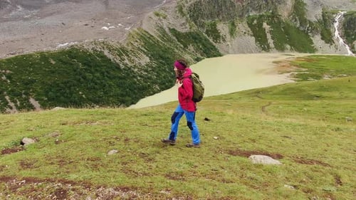 Woman Hiker with a Backpack Walks Along the Mountain with a Beautiful View of the Lake in the Summer