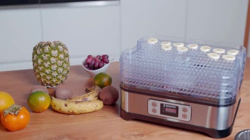 Female Caucasian places slices of fresh banana on food dehydrator rack, close up