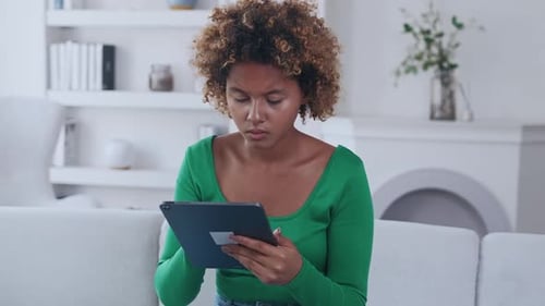 Woman Using Tablet Device on Sofa Indoors