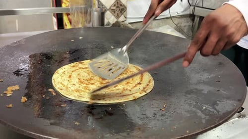Close up shot of a man preparing lacha paratha at a shop in India