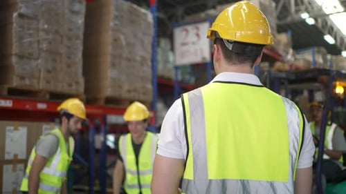 Blue collar workers are working at warehouse.