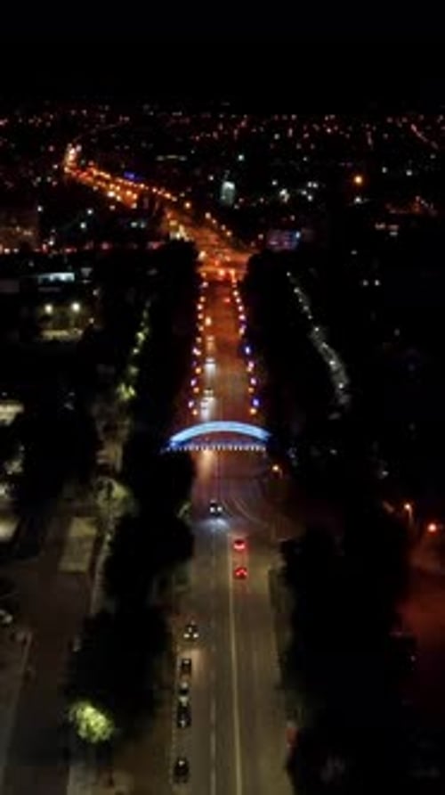 Aerial night illuminated bridge across street tilt