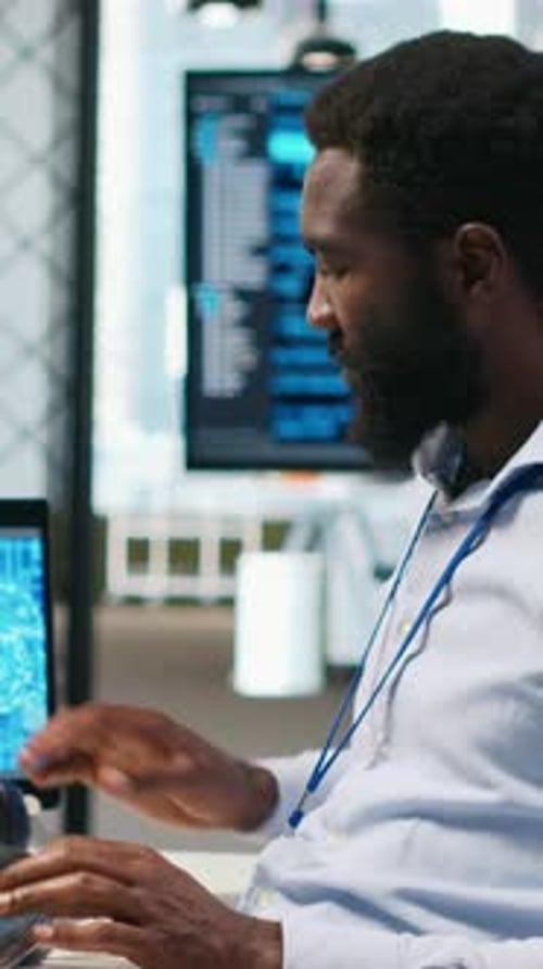 Vertical Video System Administrator at Office Desk Develops Software Using AI Listening Music