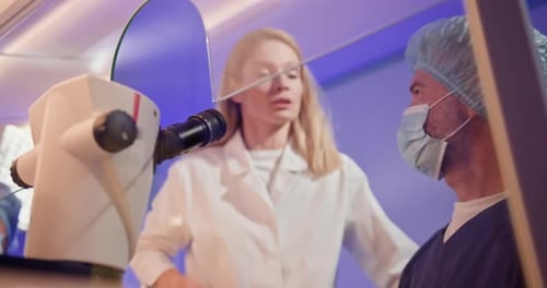 Scientists Analyzing Sample Through Microscope in Lab