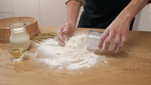 Hands Adding Flour to Wooden Table