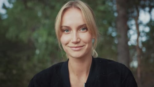 Portrait of a Young Beautiful Blond Woman in a Romantic Nature Atmosphere with a Forest in the Back