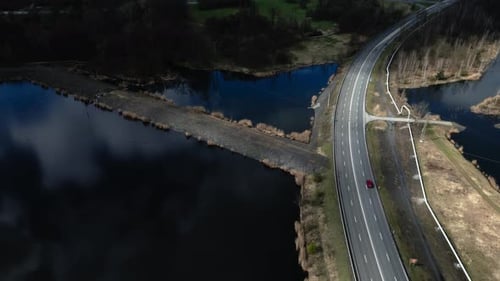 Wunderschön beleuchtete Seenlandschaft rund um die Schnellstraße mit vorbeifahrenden Autos.