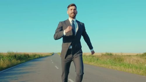 Lustiger Geschäftsmann rennt hüpfend auf einer Landstraße in der Nähe eines Weizenfeldes Freedom Concept im Freien