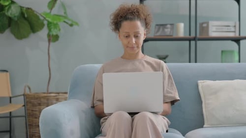 Woman Uses Laptop on Couch at Home