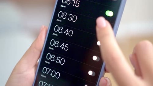 Close Up View Fingers Setting Alarm Clock for Wake Up on Smartphone Using Alarm App Technology