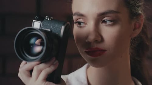 Stylish young woman photographer smiling with vintage camera in studio