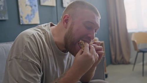 Man Bites Into a Burger at Home