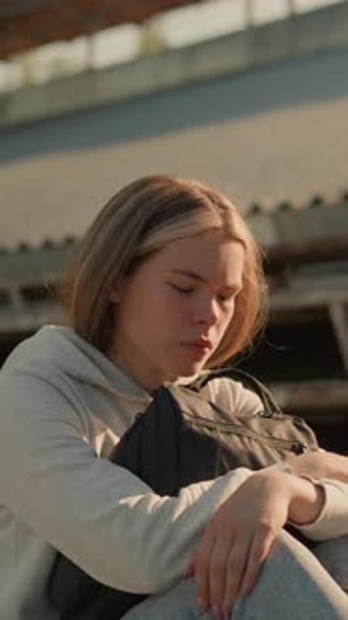 CloseUp of Thoughtful Woman Sitting Alone on Stadium Bleachers