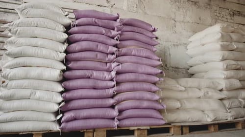 Warehouse space for storing stacks of white and purple sacks of flour lying on pallets near the wall
