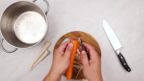 Cutting raw carrots on the cutting board. Top view of the kitchen table.