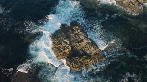 Overhead View Of Ocean Waves Crashing On The Rocky Outcrop. - aerial