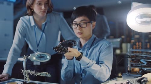 Technological Prosthetic Robot Arm is Closely Tested by Two Professional Specialists in a High Tech