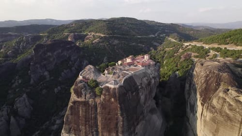 Slow arcing shot of the Meteora Rocks and the stunning Holy Trinity Monastery
